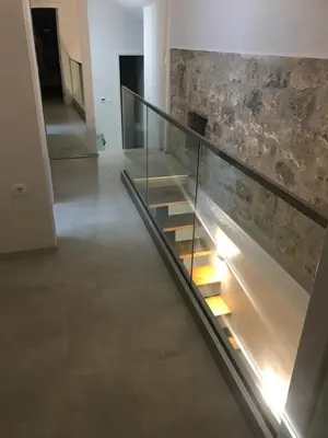 a glass staircase in a building with a stone wall at Lux Beach House M in Pržno