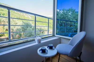 a room with a chair and a table and a window at Studio apartment Sunrise Rafailovici in Budva