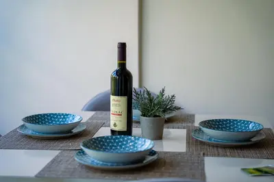 a bottle of wine sitting on a table with blue bowls at Studio apartment Sunrise Rafailovici in Budva