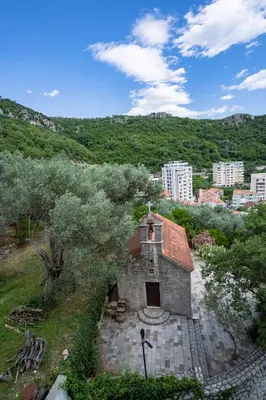 a small stone building with a city in the background at Studio apartment Sunrise Rafailovici in Budva
