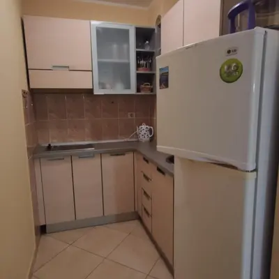 a small kitchen with a white refrigerator and cabinets at Apartman Becici beach in Becici