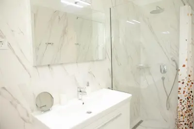 a white bathroom with a sink and a shower at Apartment MARIA Lux in Rafailovici