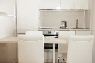 a kitchen with white counters and white chairs at Apartment MARIA Lux in Rafailovici