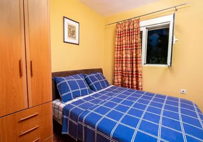 a bedroom with a blue bed and a window at APARTMANI VUKADINOVIC LUX in Budva