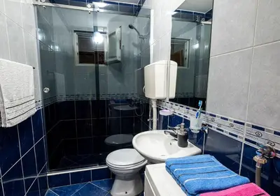a blue tiled bathroom with a toilet and a sink at APARTMANI VUKADINOVIC LUX in Budva