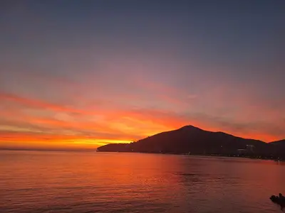 a sunset over the water with a mountain in the background at APARTMANI VUKADINOVIC LUX in Budva