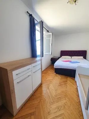 a bedroom with a bed and a dresser and a window at Apartman Lana in Petrovac na Moru