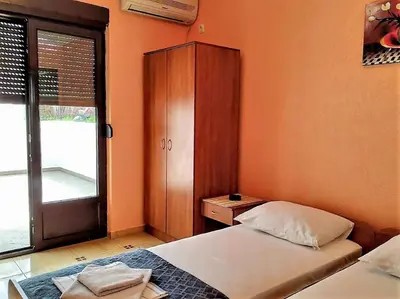 a bedroom with two beds and a cabinet and a window at Villa Budvanka Guesthouse in Budva