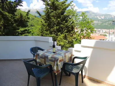 a table with a wine bottle and chairs on a balcony at Villa Budvanka Guesthouse in Budva