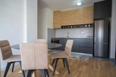 a kitchen with a table and chairs and a refrigerator at SUN apartment in Podgorica