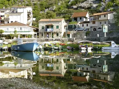 a group of boats in a marina with houses at Holiday home in Rijeka Crnojevića