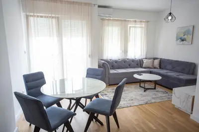 a living room with a couch and a table and chairs at Blue moon apartment in Podgorica