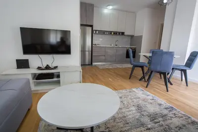 a living room with a white table and a tv at Blue moon apartment in Podgorica