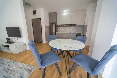 a living room with a table and chairs and a kitchen at Blue moon apartment in Podgorica