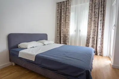 a bedroom with a bed with blue sheets and curtains at Blue moon apartment in Podgorica