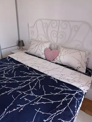 a bed with a white headboard and a pink heart pillow at Lovely apartment - Ljupki stan in Podgorica