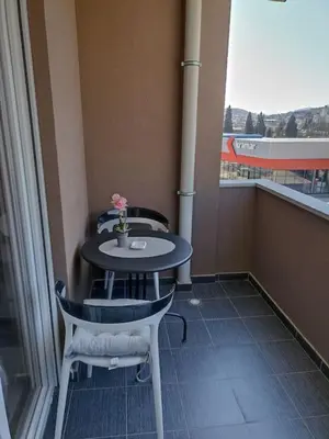 a table and chairs in a room with a window at Lovely apartment - Ljupki stan in Podgorica