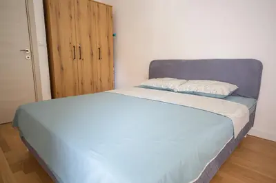 a bedroom with a blue bed and a wooden door at East Side Apartment in Podgorica