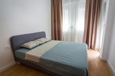 a bedroom with a bed and a window with curtains at East Side Apartment in Podgorica