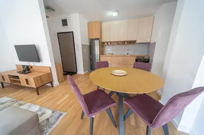 a kitchen and dining room with a table and purple chairs at East Side Apartment in Podgorica