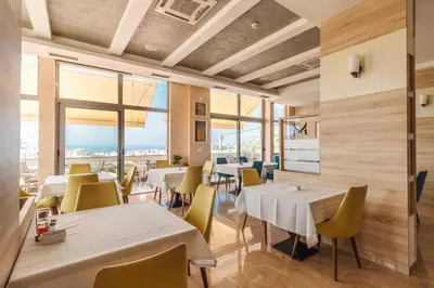a restaurant with white tables and yellow chairs at Lux Hotel M in Dobra Voda