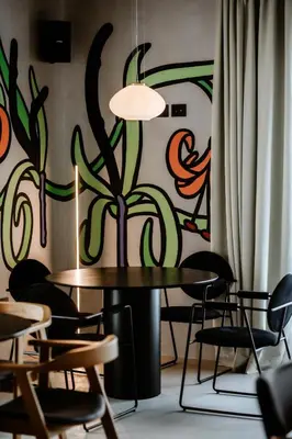 a table and chairs in a room with a painting on the wall at Hotel Septembar in Podgorica