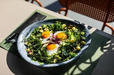 a bowl of salad with eggs on a table at Hotel Septembar in Podgorica