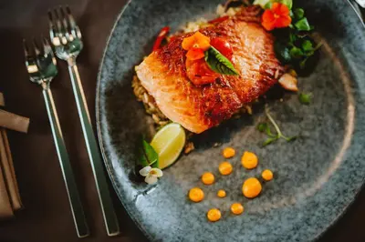 a plate of food with a piece of fish and vegetables at Hotel Septembar in Podgorica