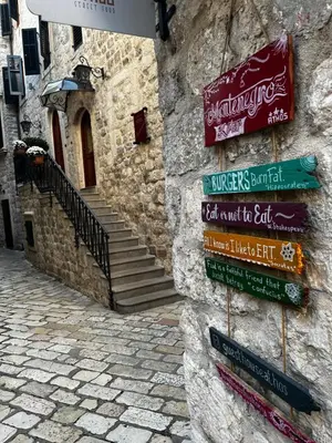 a group of signs on the side of a stone building at Puerta Apartments in Kotor