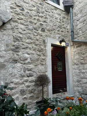 a stone building with a brown door and flowers at Puerta Apartments in Kotor