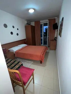 a bedroom with a bed and a chair and a window at Apartment Plazza Rafailovici in Rafailovici