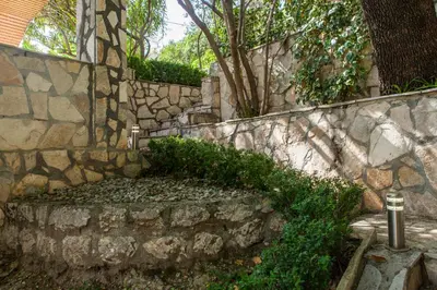 a stone retaining wall with a stone bench and trees at Vila Hrastovi in Sutomore