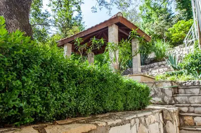 a garden with a gazebo behind a hedge at Vila Hrastovi in Sutomore