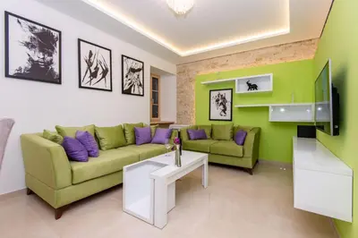 a living room with a green couch and purple pillows at apartman365kotor in Kotor