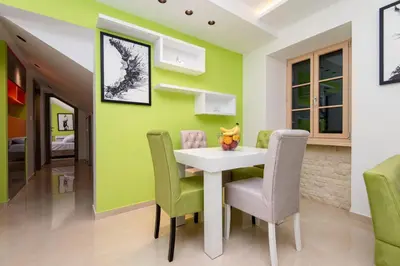 a dining room with green walls and a white table and chairs at apartman365kotor in Kotor