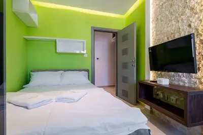 a green bedroom with a bed and a flat screen tv at apartman365kotor in Kotor
