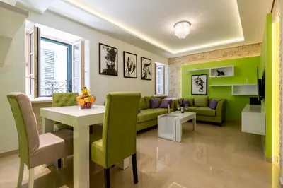 a living room with green walls and a table and chairs at apartman365kotor in Kotor
