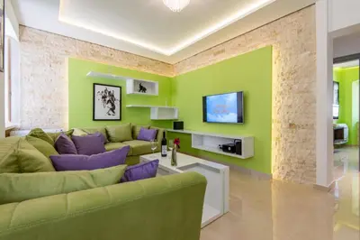a living room with green walls and purple furniture at apartman365kotor in Kotor