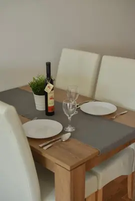 a wooden table with two plates and a bottle of wine at Sofija in Ulcinj