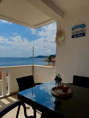 a balcony with a table and a view of the ocean at Pine&Sea Beach Retreat in Sveti Stefan