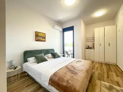 a bedroom with a large bed with a green headboard at MaNora in Ulcinj