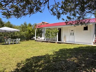 a white house with a red roof and a yard at Vikendica Nina in Čanj
