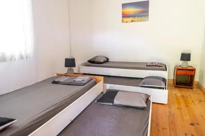 a room with three beds and a painting on the wall at Vikendica Nina in Čanj