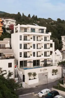a large white building with cars parked in front of it at G Star Hotel in Sutomore