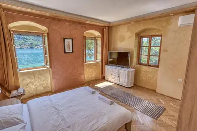 a bedroom with a bed and a tv and windows at Stone Home Kotor in Dobrota