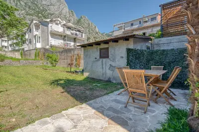 a patio with a table and chairs in a yard at Stone Home Kotor in Dobrota