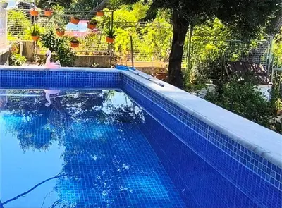 a blue swimming pool with a reflection in the water at House in the pines in Sutomore