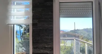 a window with a view of a house at House in the pines in Sutomore