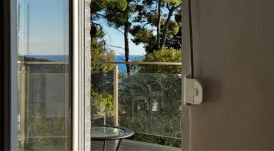 an open door to a balcony with a glass table at House in the pines in Sutomore