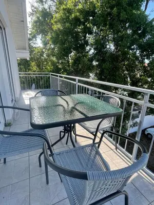 a glass table and chairs on a balcony at Days Inn Long Beach in Ulcinj